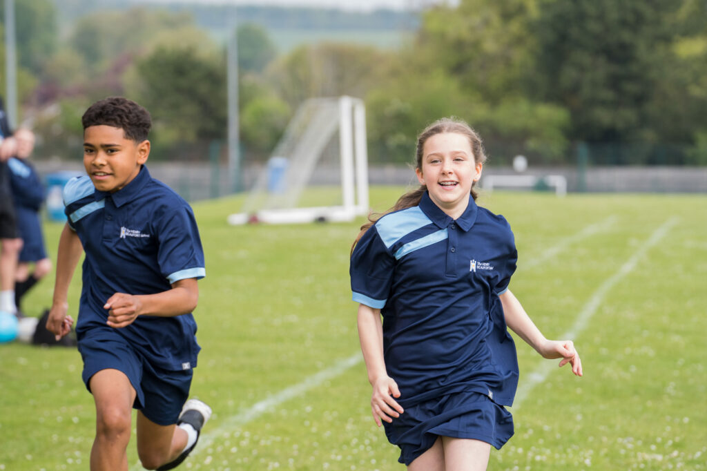 Students running across pitch during sports lesson