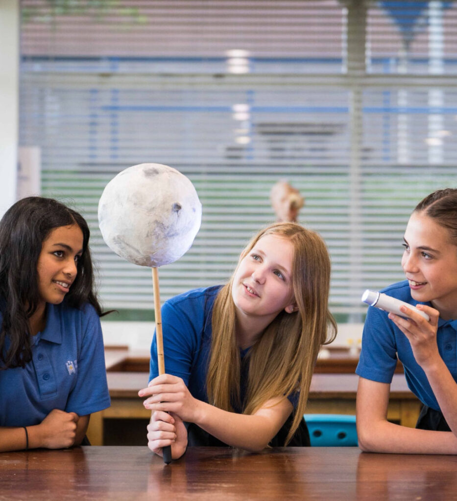 Students looking in awe at prop re-creation of the moon during science lesson.
