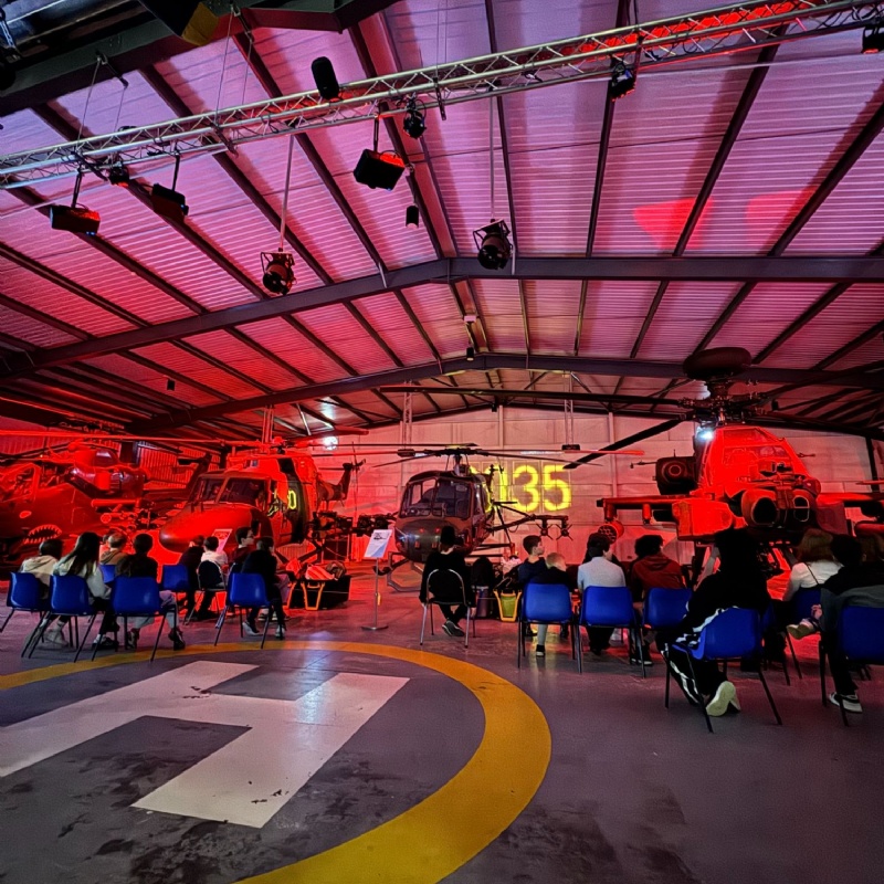 Photo of students on chairs admiring helicopters within a hanger as part of the Army Flying Museum Trip.
