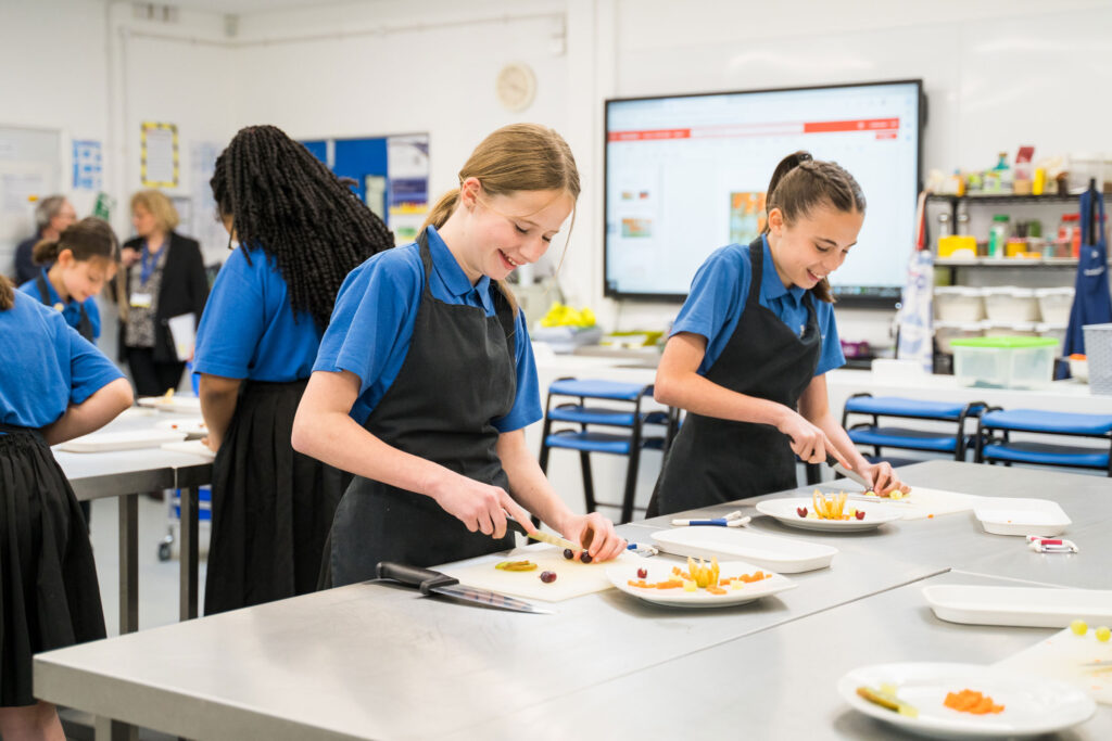 Two students cutting fruit and preparing dishes during cooking class.